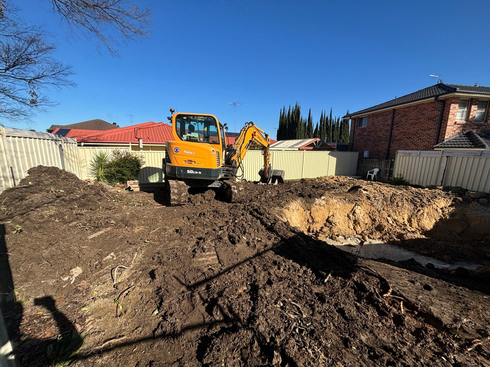 Backyard pool excavation site with spoil stockpiled ready for cart-away